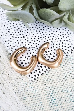  A pair of chunky gold-tone hoop earrings with a modern, curved silhouette and a polished finish. A versatile accessory for elevating any look.