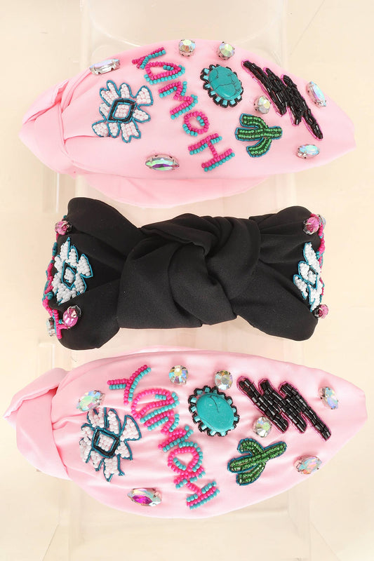 A set of three knotted headbands in pink and black, featuring intricate beaded designs of cacti, turquoise stones, lightning bolts, and the word "Howdy."