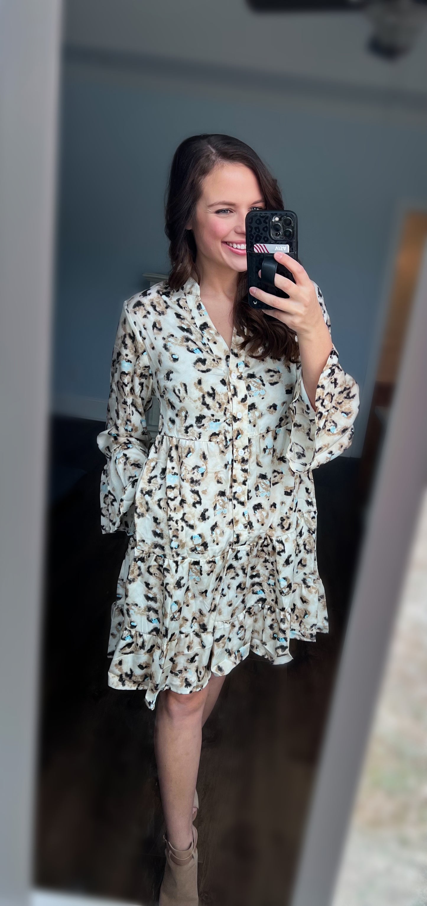 A tiered button-down dress featuring a stylish leopard print with subtle pops of turquoise. Designed with long flowy sleeves, a relaxed silhouette, and lightweight fabric for effortless style. Styled with neutral ankle booties for a modern Western-inspired look. Perfect for brunch, casual outings, or transitioning between seasons.